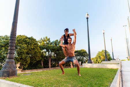 Beautiful man and woman doing acroyoga in the city park lawnの写真素材
