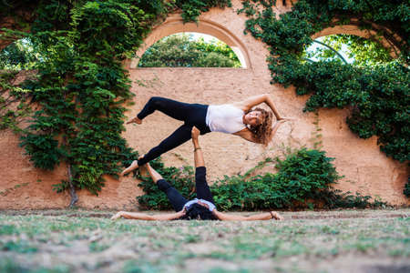 Two beautiful women doing acroyoga in the garden or parkの写真素材