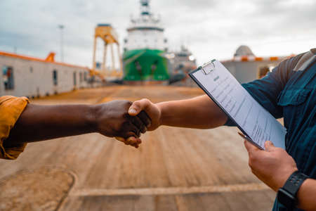 marine contractor businessman handshaking with worker on the shipの写真素材