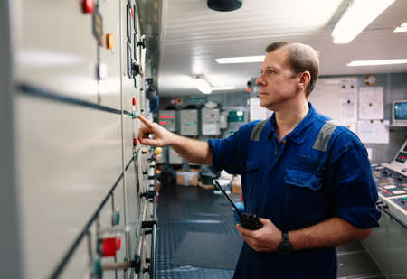 Marine engineer officer controlling vessel engines and propulsion in engine control roomの写真素材
