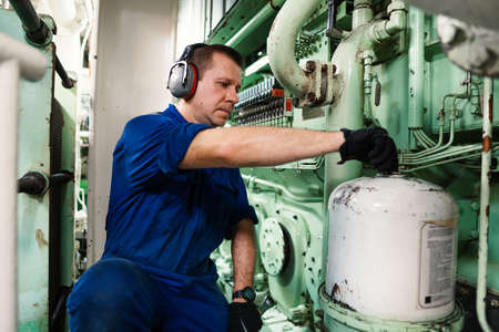 Marine engineer officer controlling vessel enginesand propulsion in engine control room ECR