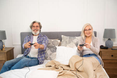 Happy elderly grandparents having fun playing video gamesの写真素材