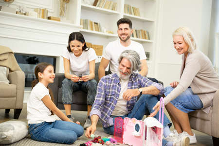Big family having fun time together playing with child and her dollhouseの写真素材