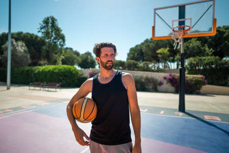 basketball player standing on basketball court outdoors in summerの写真素材