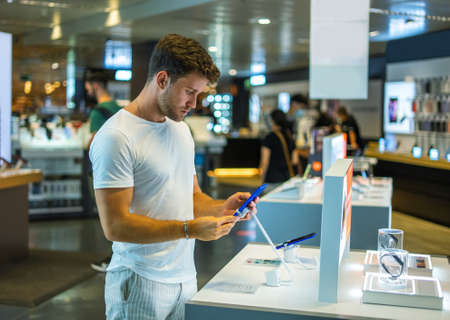 Customer checking phone in electronics storeの写真素材
