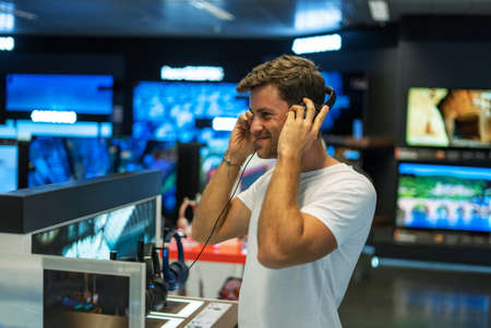 Happy buyer choosing headphones in storeの写真素材