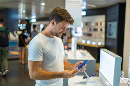 Smiling customer testing smartphone in storeの写真素材