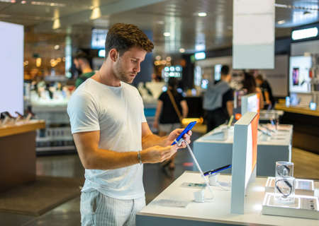 Buyer with smartphone in electronics shopの写真素材