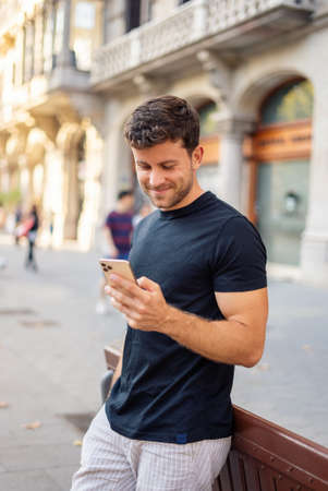 Cheerful man using smartphone on city streetの写真素材