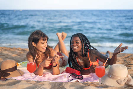 Happy diverse girlfriends chilling on beachの写真素材