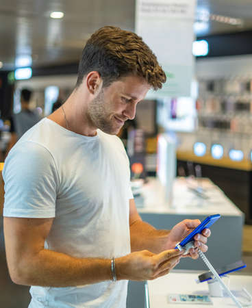 Smiling customer testing smartphone in storeの写真素材