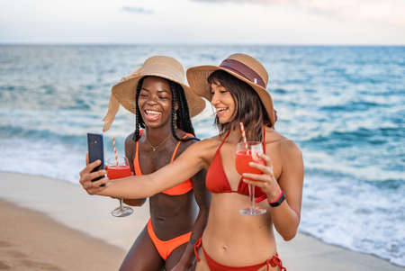 Lively diverse women taking self portrait on beachの写真素材