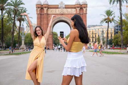 Happy female tourists taking pictures on city squareの写真素材