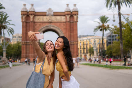 Stylish female travelers taking selfie in cityの写真素材