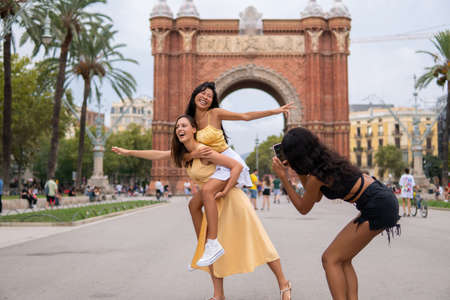 Cheerful women taking photo on city squareの写真素材