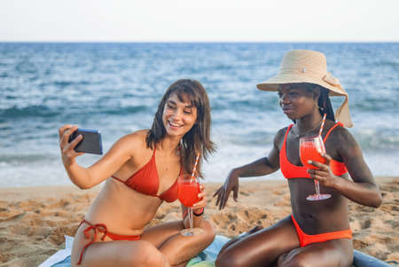 Happy girlfriends taking selfie on beachの写真素材