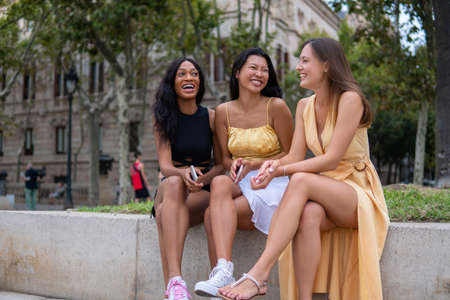 Happy diverse girlfriends chatting on city streetの写真素材