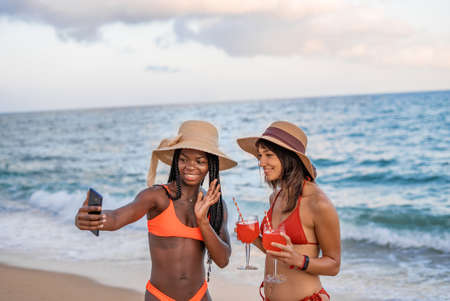 Girlfriends making video call on beachの写真素材