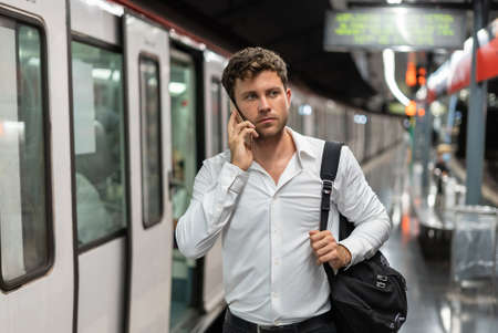 Manager speaking on cellphone on platformの写真素材