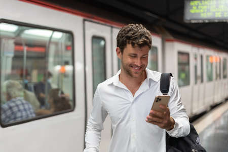 Cheerful businessman using smartphone on stationの写真素材