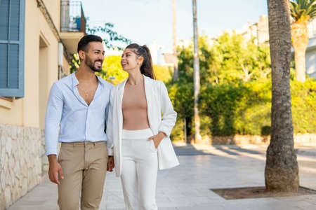 Delighted Hispanic couple walking together in city streetの写真素材