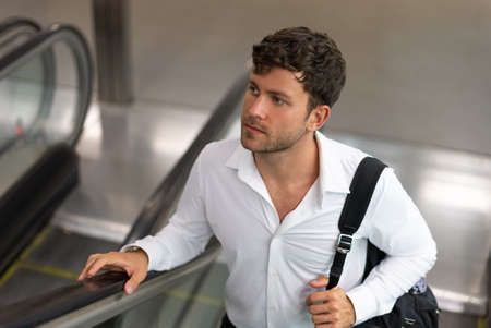Businessman riding escalator in airportの写真素材