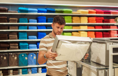Man selecting bedclothes in shopの写真素材