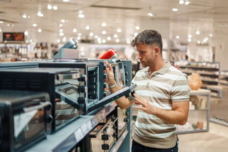 Man looking inside microwave oven in shopの写真素材