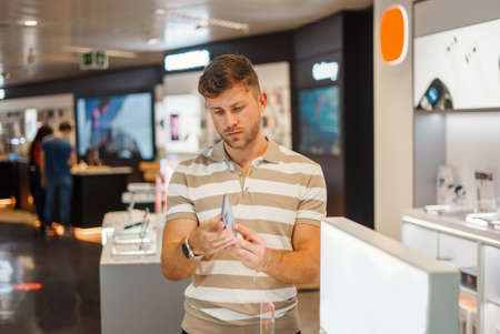 Man examining smartphone in technology shopの写真素材