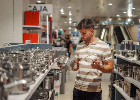 Man selecting saucepan in storeの写真素材