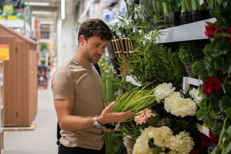 Man choosing potted plant in storeの写真素材
