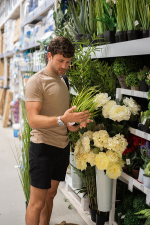 Man examining potted grass in shopの写真素材