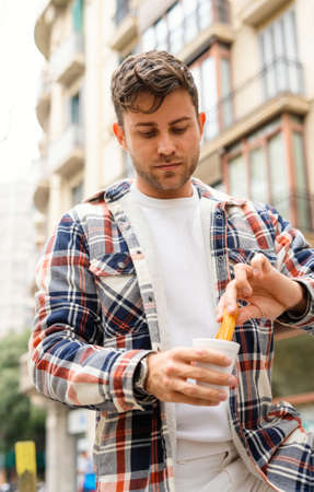 Man eating sweet churros in city streetの写真素材