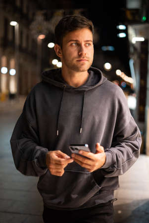 Male with cellphone walking on evening street