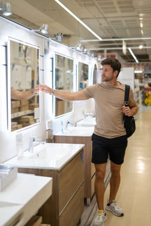 Man choosing bathroom mirror in storeの写真素材