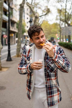 Glad man eating sweet churros in cityの写真素材