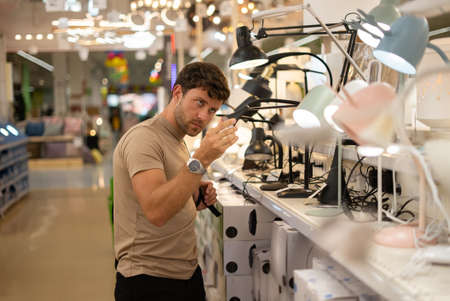 Man in store with house goods choosing lampの写真素材