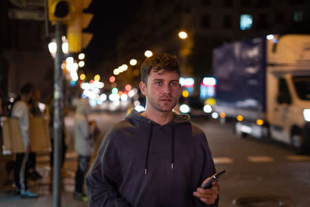 Man with smartphone on street at nightの写真素材