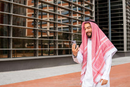 Arab male using cellphone on streetの写真素材
