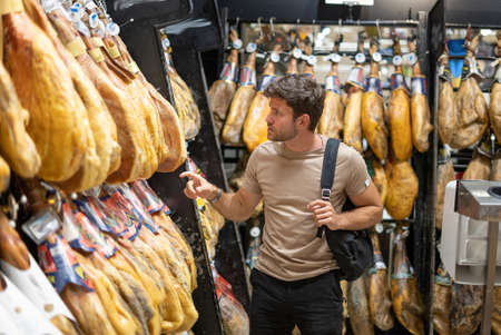Man choosing jamon in shop