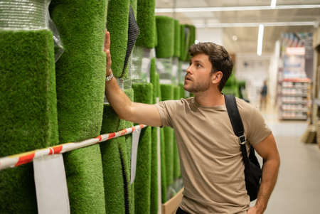 Man in gardening store looking at fake grassの写真素材