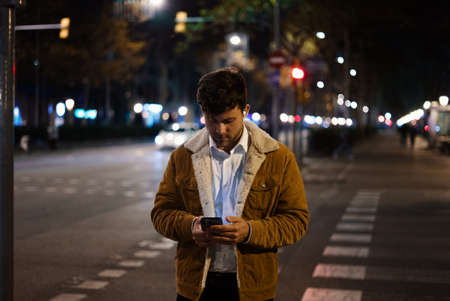 Man browsing smartphone in night city