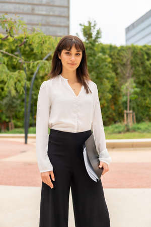 Young confident european business woman holding folder with contract wihle standing on city streetの写真素材