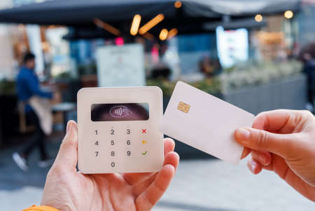 Woman making purchase on POS terminal in street cafeの写真素材