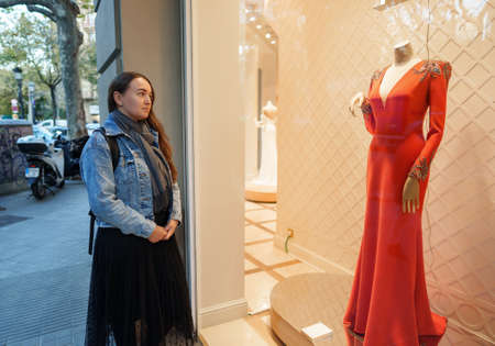 Woman dreaming of red dress in storeの写真素材