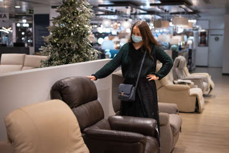 Woman examining armchair in storeの写真素材