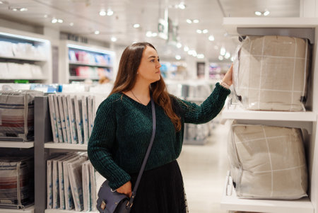Young focused woman doing shopping in store mall in bedding departmentの写真素材
