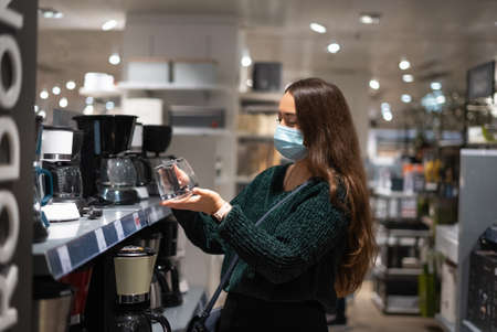 Woman in mask choosing coffee potの写真素材