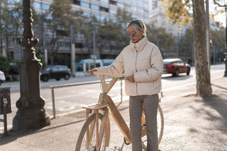 Woman with eco bike on sidewalkの写真素材