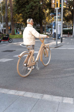 Positive woman with wooden eco bike crossing streetの写真素材